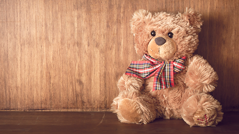 urso de peluche castanho claro encostado a uma parede castanha